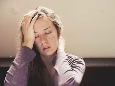Woman with a pained expression holding her head, illustrating symptoms of stress or discomfort related to gas leak exposure.