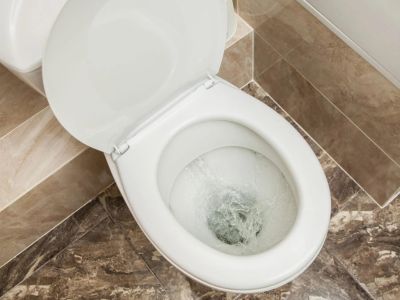 Toilet flushing in a modern bathroom setting, emphasizing the importance of regular plumbing maintenance for optimal performance and prevention of issues.