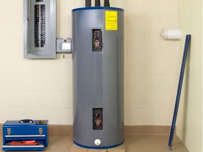 Water heater in a utility room with maintenance tools, highlighting the importance of annual plumbing maintenance for optimal performance and efficiency.